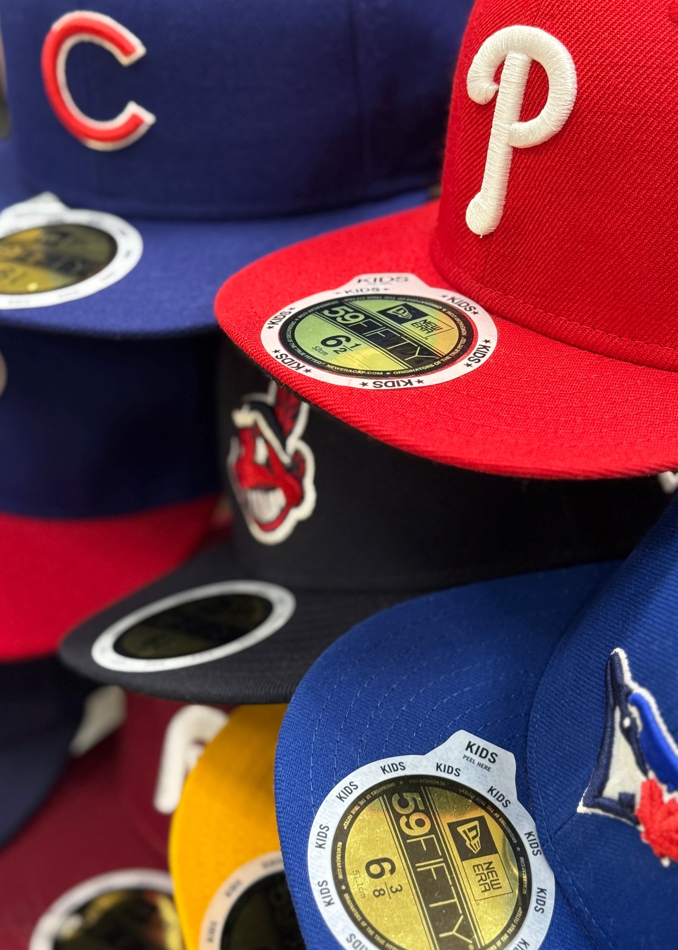 Collection of kids baseball caps with various team logos